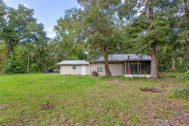 rear view of house with a yard and a sunroom