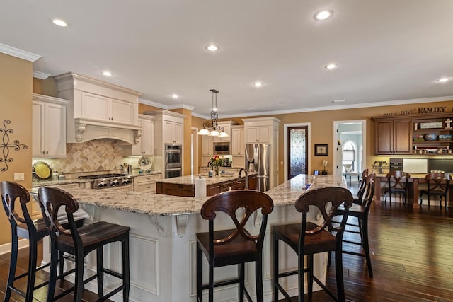 kitchen featuring appliances with stainless steel finishes, a kitchen bar, dark hardwood / wood-style flooring, hanging light fixtures, and a large island