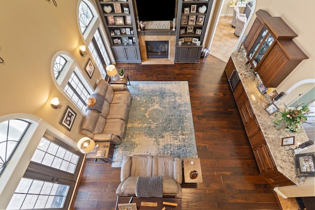 living room featuring a high ceiling, a tiled fireplace, and dark hardwood / wood-style flooring