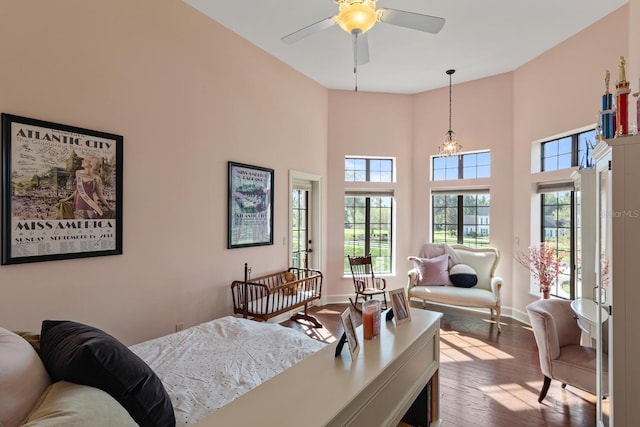 bedroom with hardwood / wood-style floors, a high ceiling, and ceiling fan