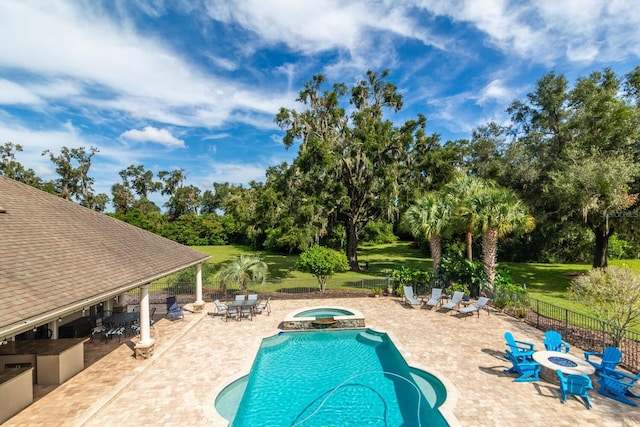 view of pool featuring a lawn, an in ground hot tub, a patio, and a fire pit