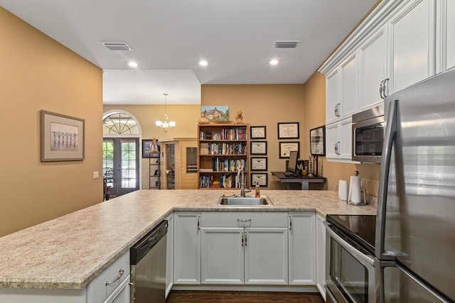 kitchen with kitchen peninsula, white cabinets, appliances with stainless steel finishes, french doors, and sink