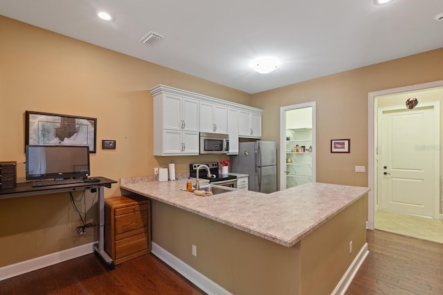 kitchen with appliances with stainless steel finishes, dark hardwood / wood-style flooring, kitchen peninsula, white cabinets, and a breakfast bar area