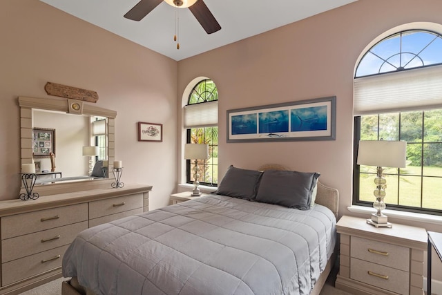 carpeted bedroom featuring lofted ceiling, multiple windows, and ceiling fan