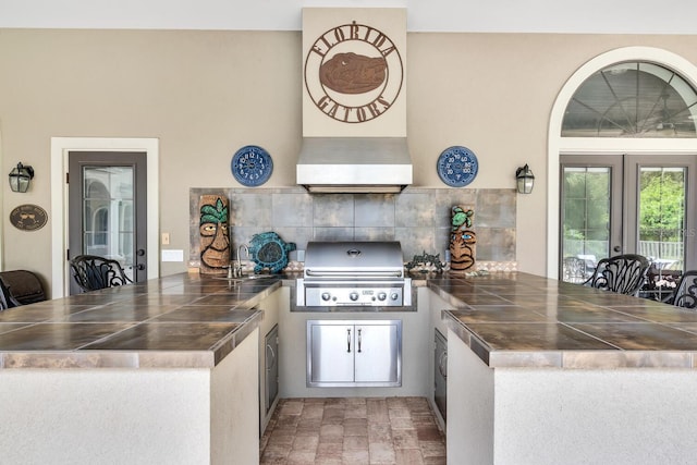 kitchen featuring kitchen peninsula, backsplash, french doors, sink, and ventilation hood