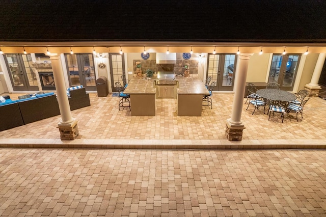 patio at night featuring french doors and an outdoor kitchen