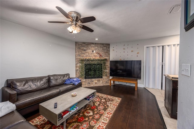 living room featuring a fireplace, light wood-type flooring, and ceiling fan