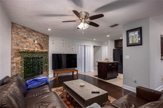 living room featuring light hardwood / wood-style flooring, a textured ceiling, and ceiling fan