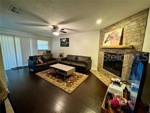 living room featuring a large fireplace, dark hardwood / wood-style floors, and ceiling fan