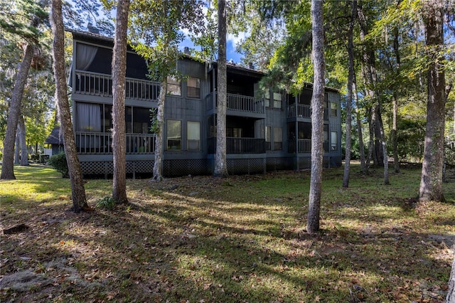 rear view of property featuring a balcony and a yard