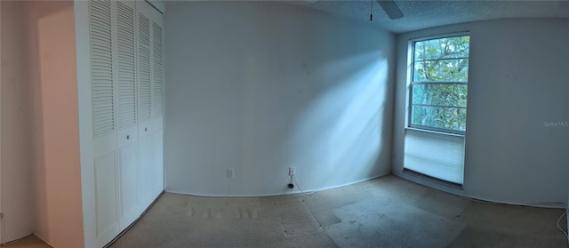 unfurnished bedroom featuring a closet, a textured ceiling, carpet floors, and ceiling fan