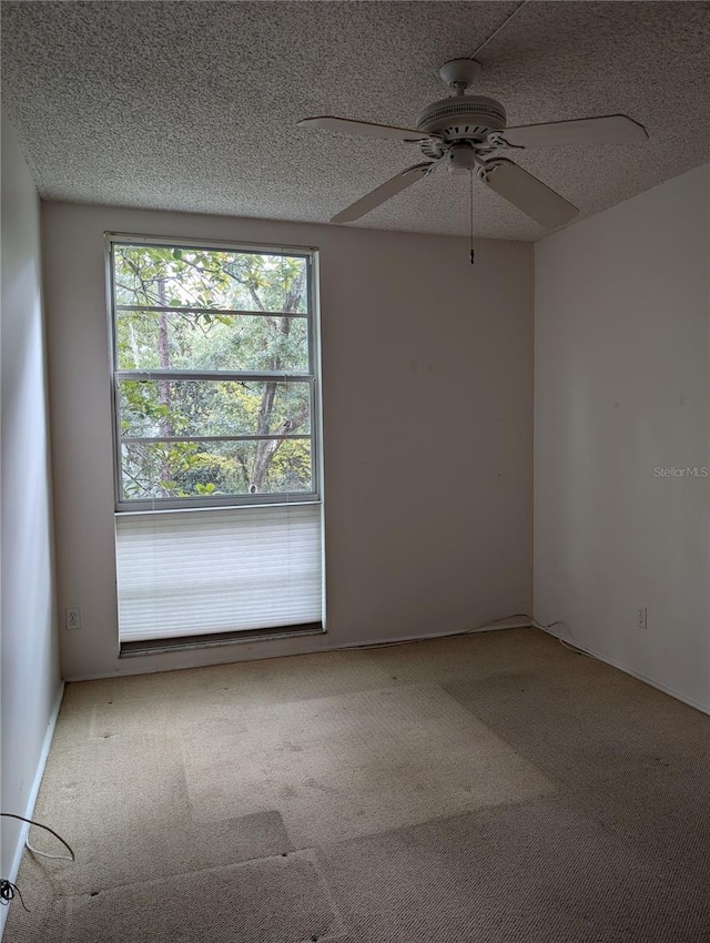 carpeted spare room with a textured ceiling and ceiling fan