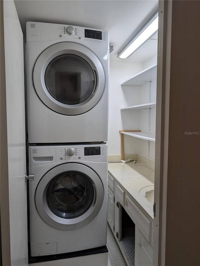 laundry area featuring stacked washer / dryer and light tile patterned floors