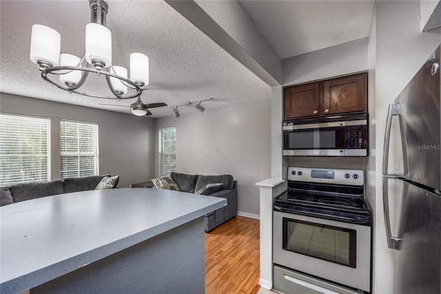 kitchen featuring dark brown cabinets, light wood-type flooring, appliances with stainless steel finishes, a textured ceiling, and ceiling fan