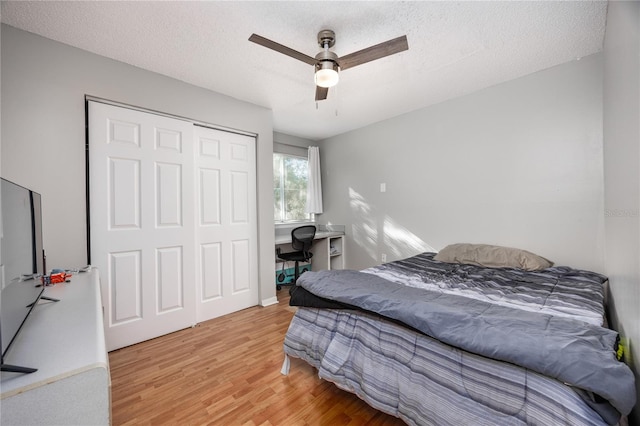 bedroom with a closet, a textured ceiling, wood-type flooring, and ceiling fan