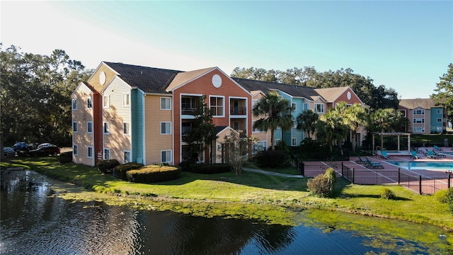 exterior space with a yard, a balcony, a water view, a patio, and a fenced in pool