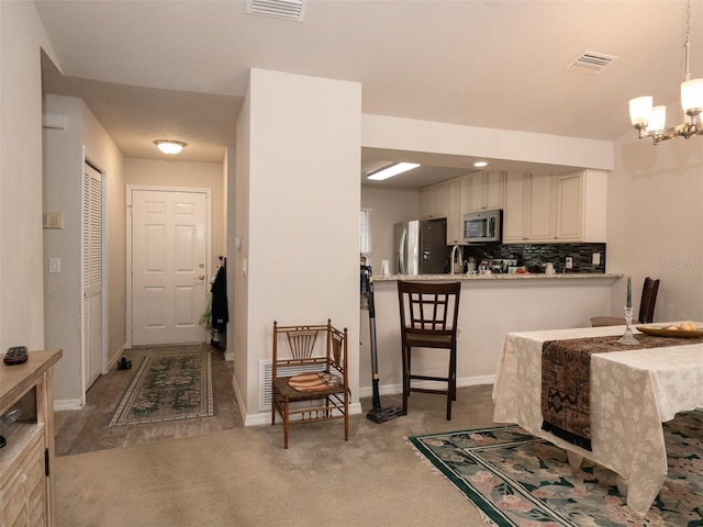 carpeted dining area with a notable chandelier and sink