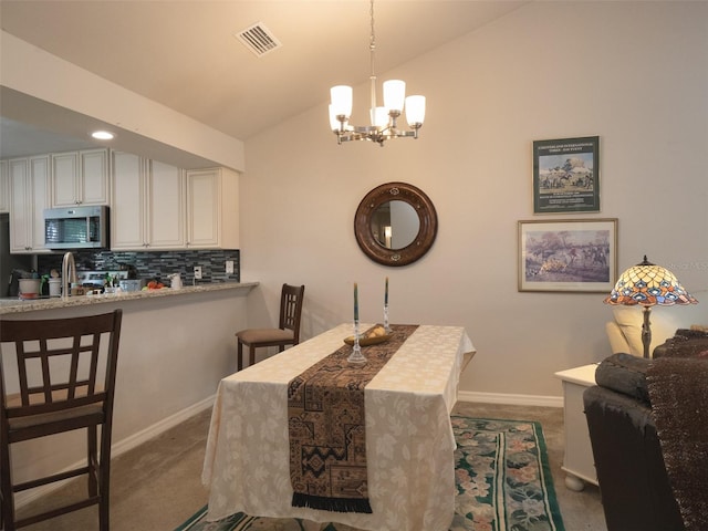 carpeted dining room featuring lofted ceiling and an inviting chandelier