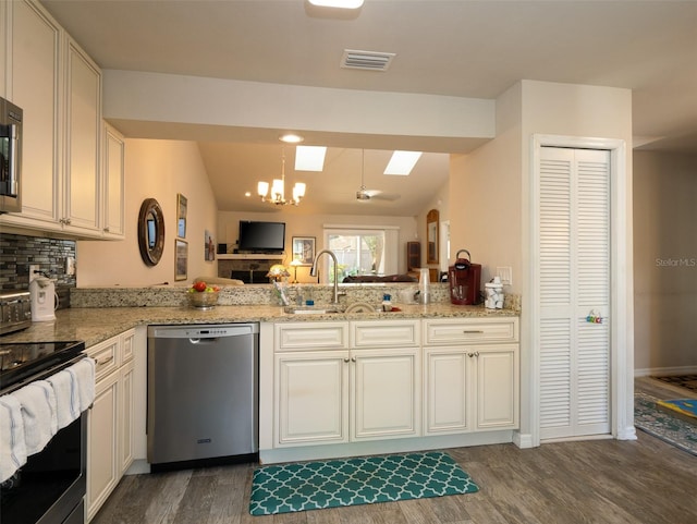 kitchen with sink, appliances with stainless steel finishes, vaulted ceiling with skylight, and dark hardwood / wood-style flooring