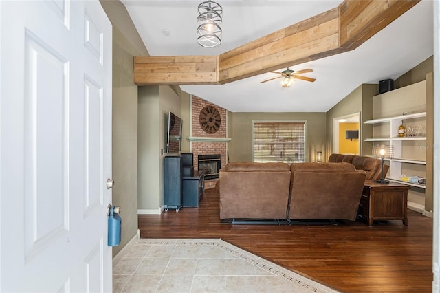 living room featuring hardwood / wood-style floors, vaulted ceiling, a brick fireplace, and ceiling fan