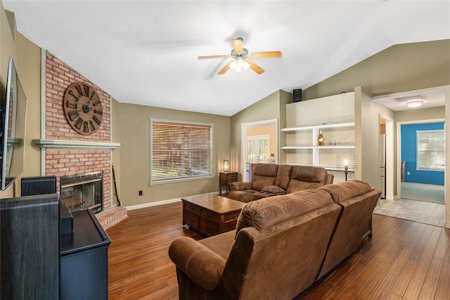 living room with ceiling fan, vaulted ceiling, a brick fireplace, and dark hardwood / wood-style floors