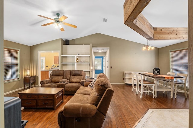 living room with hardwood / wood-style floors, a wealth of natural light, ceiling fan with notable chandelier, and vaulted ceiling