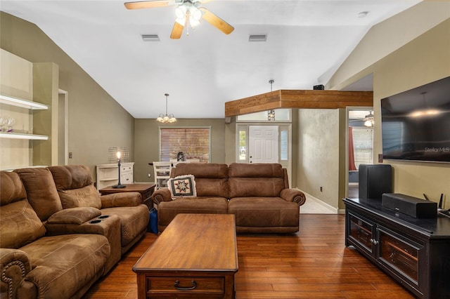 living room with dark wood-type flooring, a healthy amount of sunlight, vaulted ceiling, and ceiling fan with notable chandelier