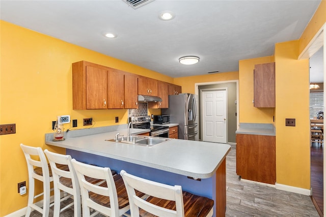 kitchen with kitchen peninsula, stainless steel appliances, dark wood-type flooring, and sink