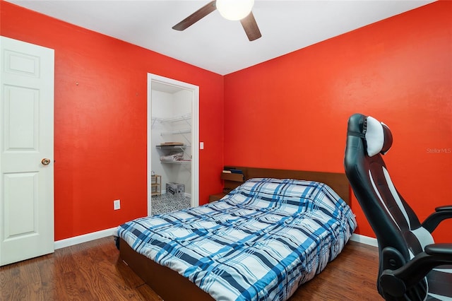 bedroom with a closet, a spacious closet, dark wood-type flooring, and ceiling fan