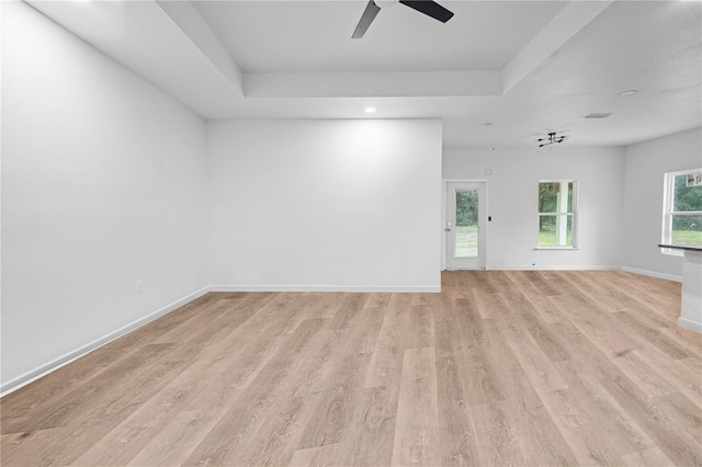 spare room with ceiling fan, a tray ceiling, and light hardwood / wood-style flooring