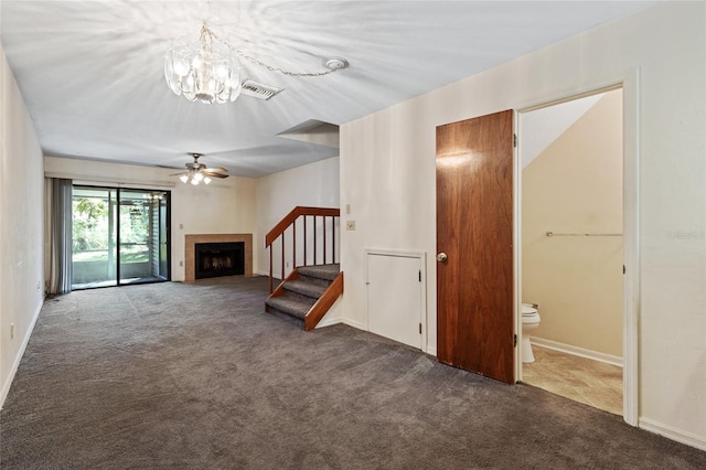 unfurnished living room with ceiling fan with notable chandelier and dark carpet