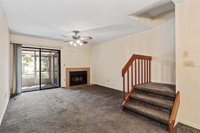 unfurnished living room with dark carpet, a tiled fireplace, and ceiling fan