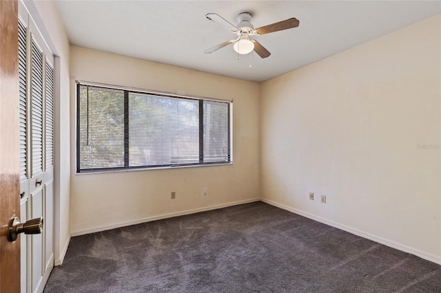 unfurnished bedroom featuring dark colored carpet, a closet, and ceiling fan