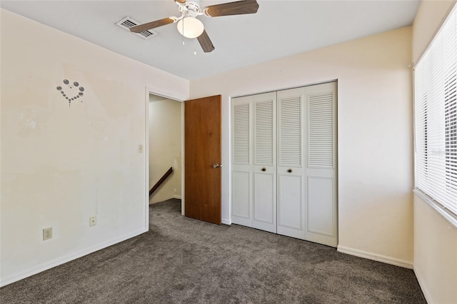 unfurnished bedroom featuring dark carpet, multiple windows, a closet, and ceiling fan