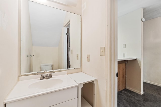 bathroom with vanity, vaulted ceiling, and toilet