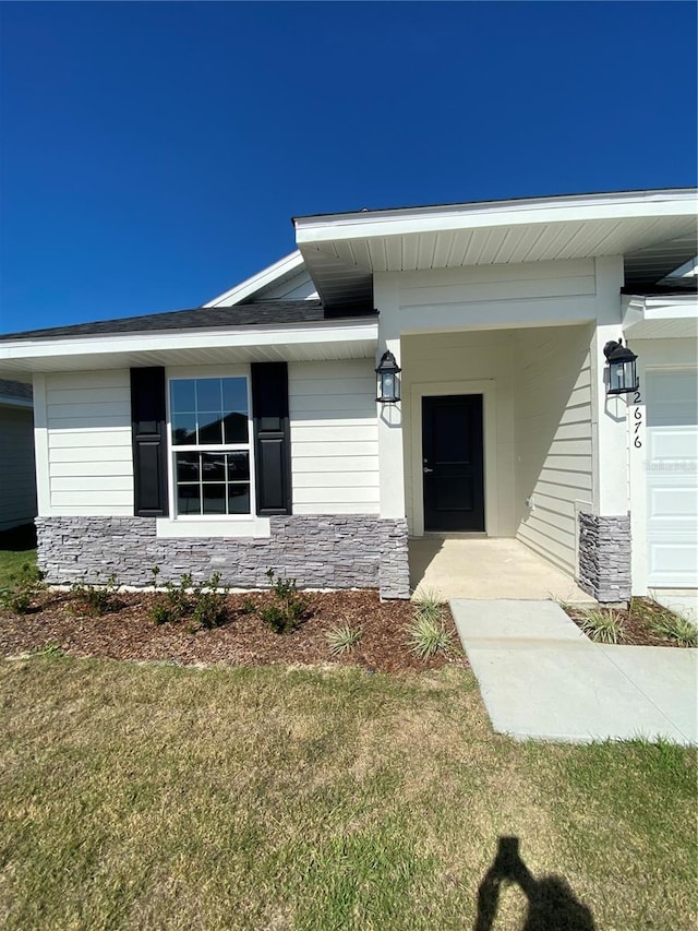 view of exterior entry with a yard and a garage