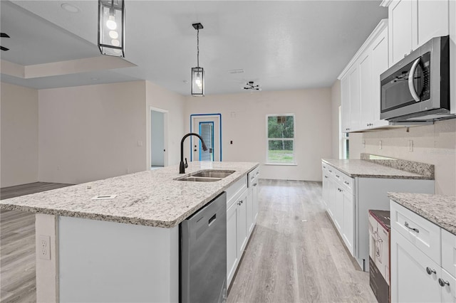 kitchen featuring appliances with stainless steel finishes, sink, light wood-type flooring, an island with sink, and white cabinetry