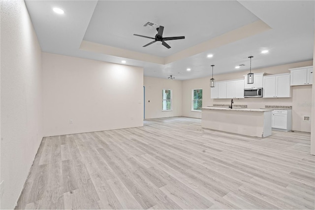 unfurnished living room with light hardwood / wood-style floors and a tray ceiling