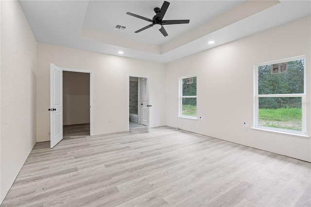 unfurnished bedroom with light hardwood / wood-style flooring, a raised ceiling, and ceiling fan