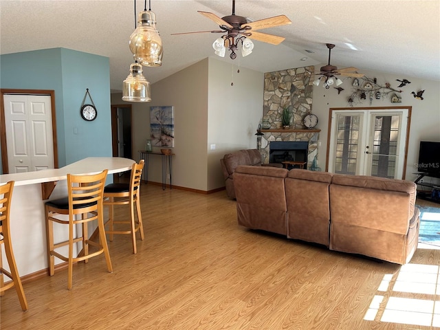 living room featuring a fireplace, french doors, light wood-type flooring, and lofted ceiling