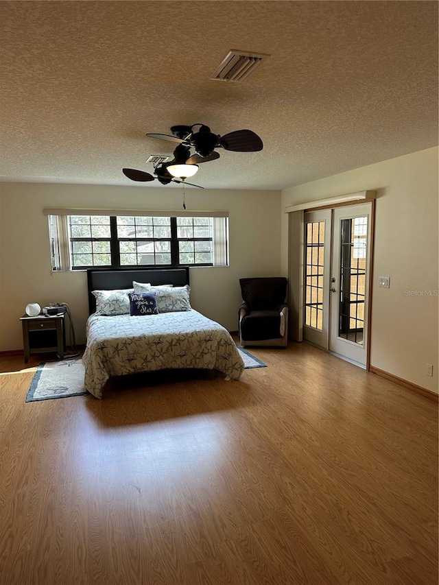 bedroom featuring a textured ceiling, light wood-type flooring, access to outside, and ceiling fan