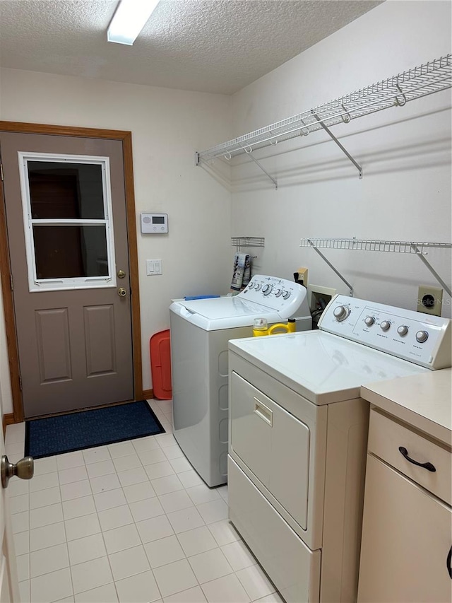 laundry area with washer and clothes dryer, light tile patterned floors, and a textured ceiling