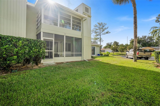 back of house featuring a lawn and a sunroom