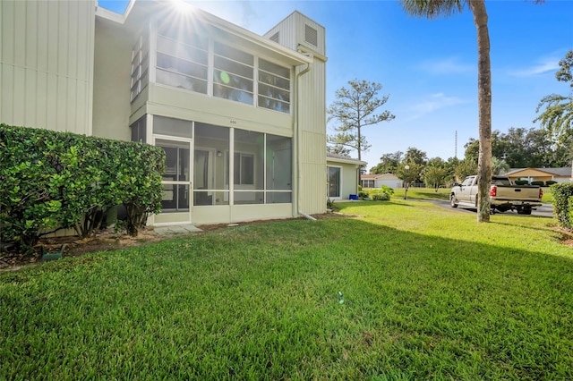 back of property featuring a lawn and a sunroom