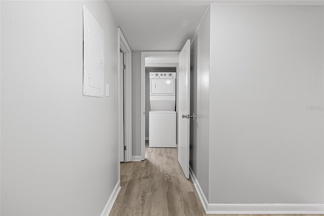 hall featuring light hardwood / wood-style flooring, electric panel, and stacked washer / dryer