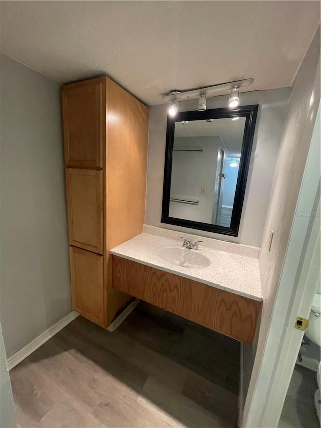 bathroom with toilet, hardwood / wood-style flooring, vanity, and track lighting