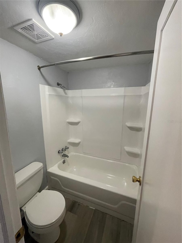 bathroom featuring toilet, hardwood / wood-style flooring, and shower / tub combination