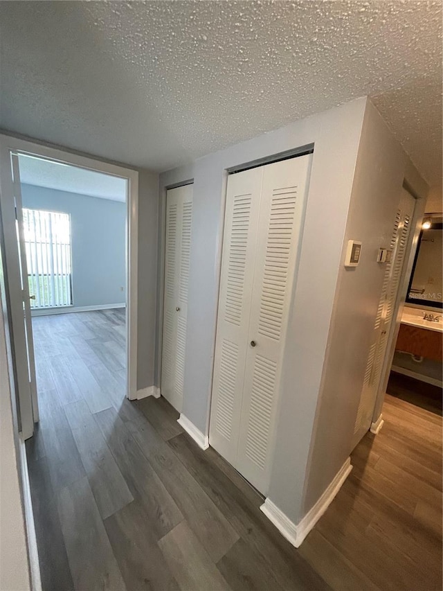 hall with a textured ceiling and dark hardwood / wood-style flooring