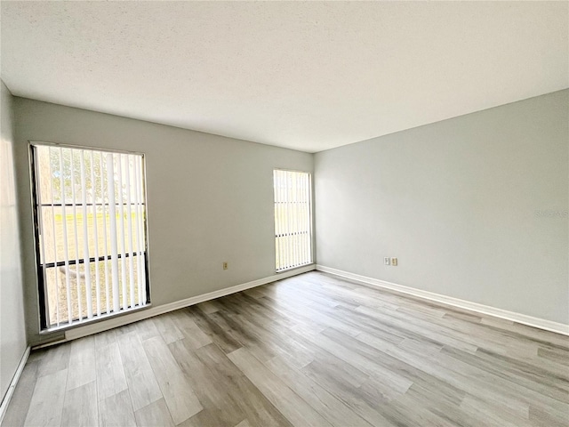 spare room featuring a healthy amount of sunlight, a textured ceiling, and light wood-type flooring