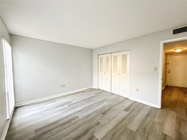 unfurnished bedroom featuring a textured ceiling, light wood-type flooring, and a closet